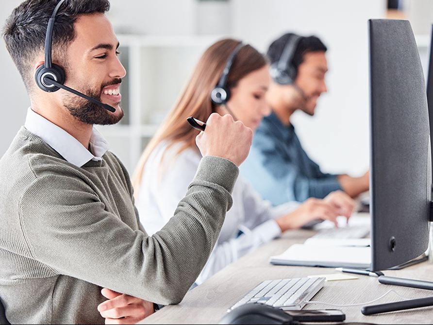 Equipo del call center atendiendo llamadas con diadema frente al computador