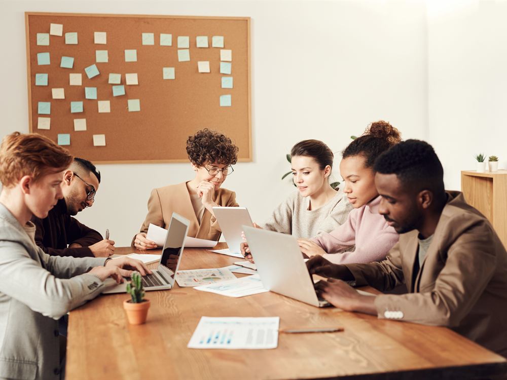 Equipo de trabajo reunido en una mesa con computadores y documentos